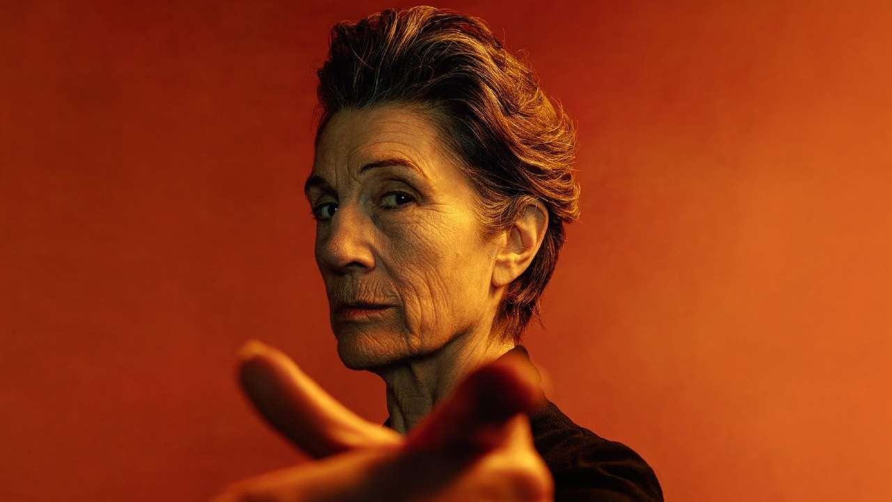 Actress Harriet Walter looking direct to camera with orange background