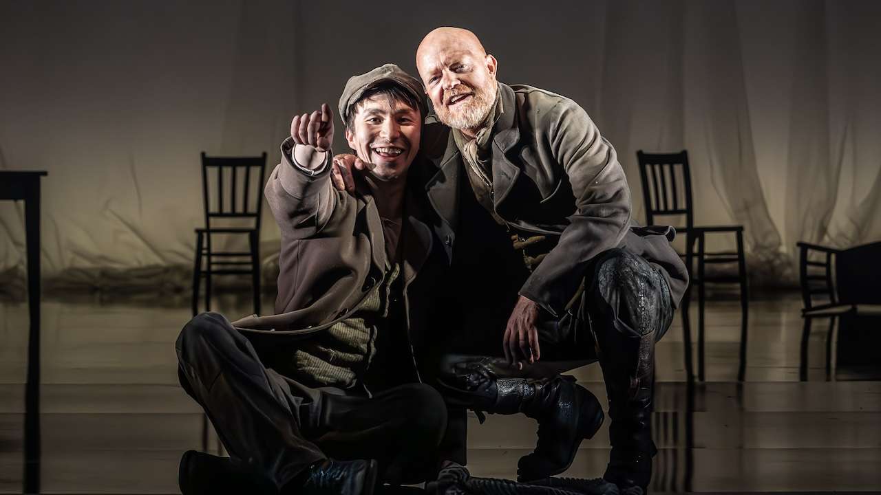 Two men crouched down looking out. Brandon Grace (Charley Hexam) and Jake Wood (Gaffer Hexam) in London Tide at the National Theatre (c) Marc Brenner