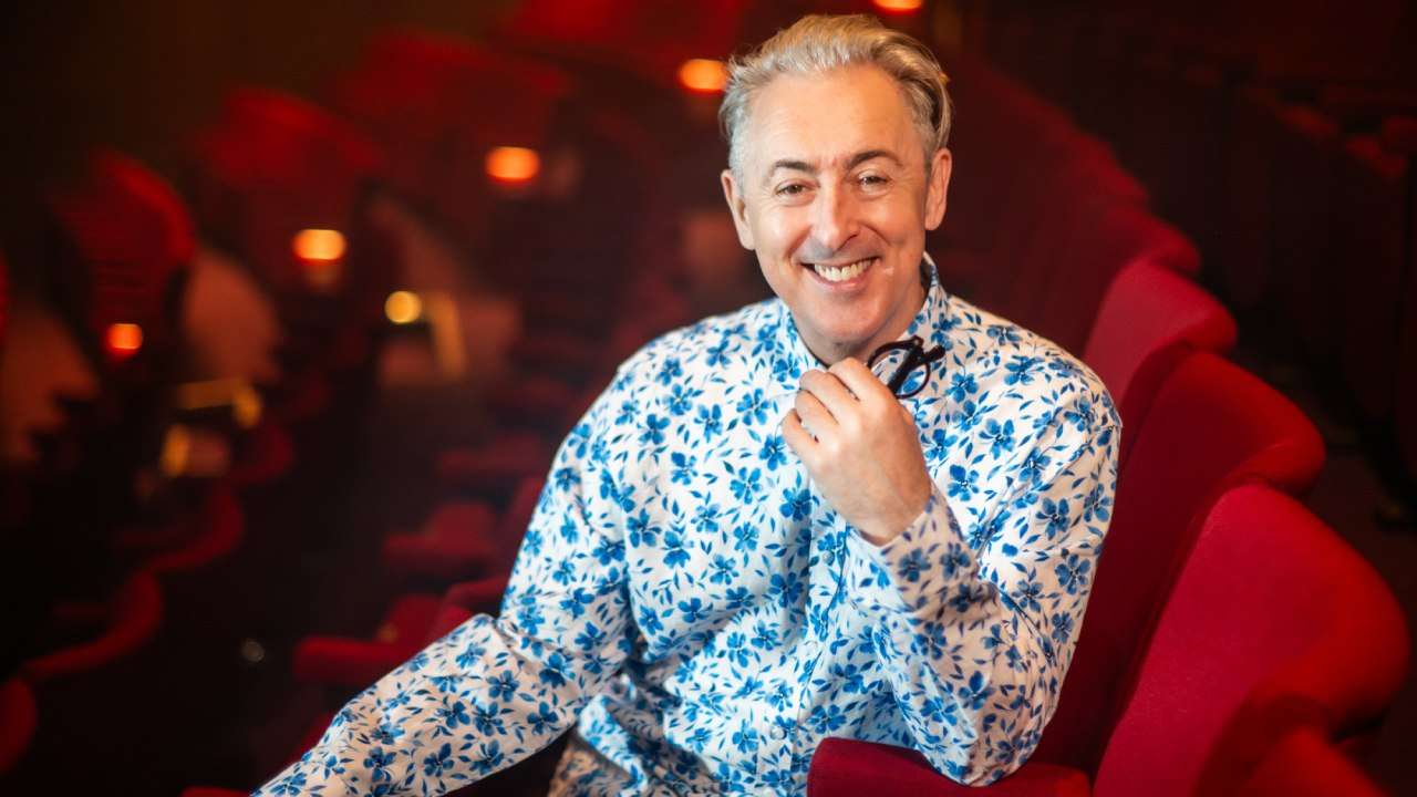 Alan Cumming sat in chair looking to camera at Pitlochry Festival Theatre