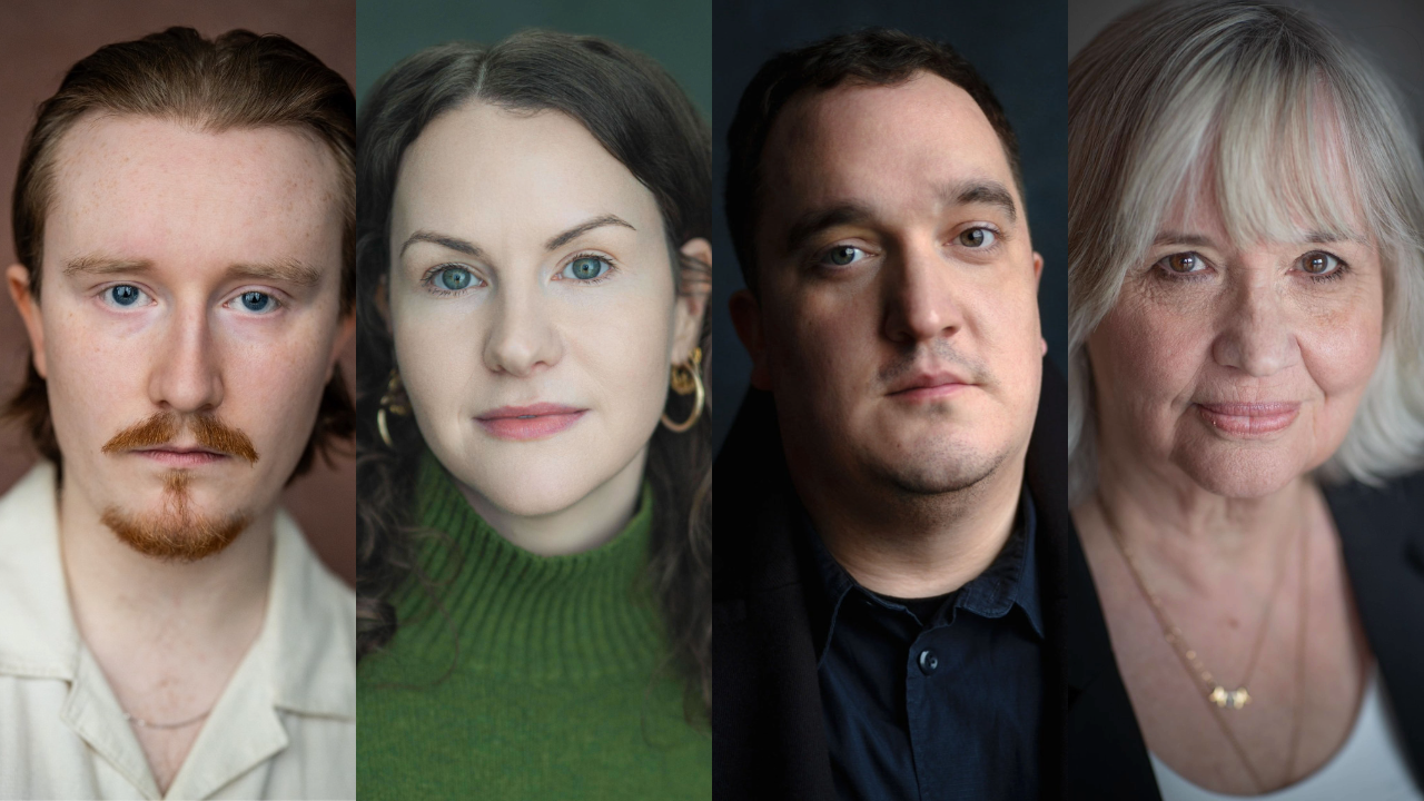 Group portrait of four adults facing the camera: a red‑haired man, a woman in a green sweater, a man in a dark blazer, and an older woman with gray hair (left to right).