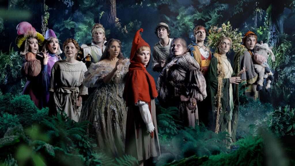 A group of costumed characters in a moonlit forest, facing the camera.