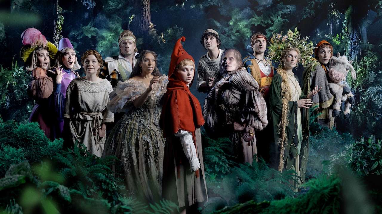 A group of costumed characters in a moonlit forest, facing the camera.
