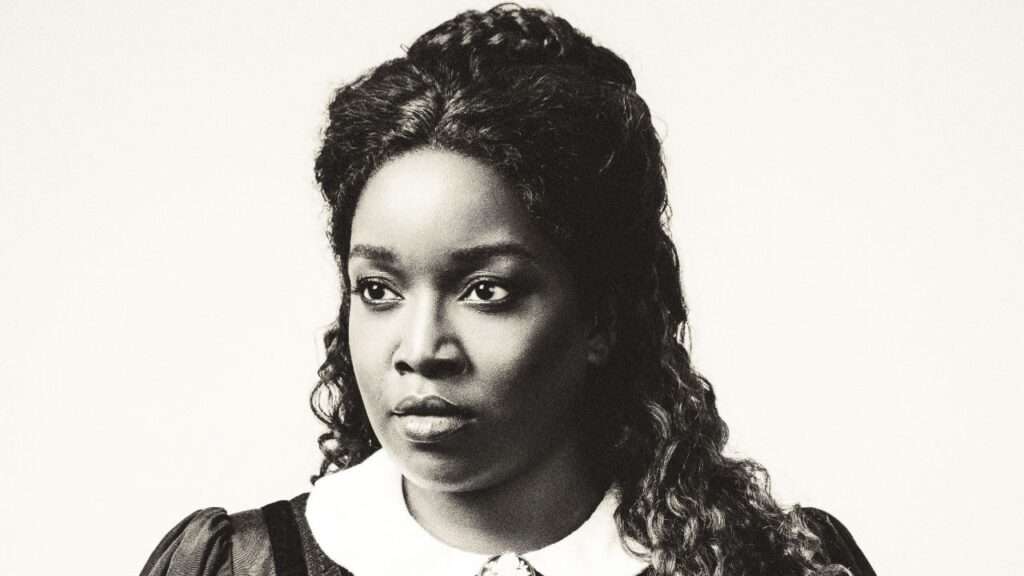 Black-and-white portrait of a woman with curly hair and a white collared blouse, gazing left.