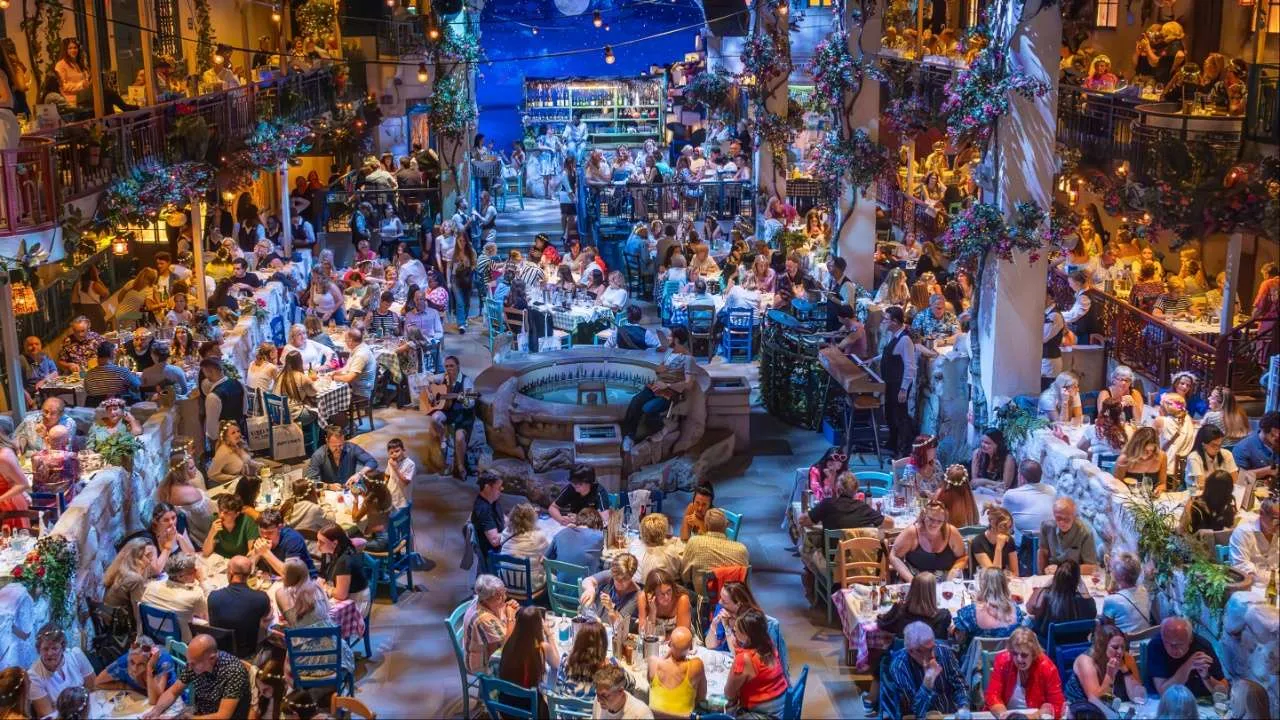 Bird's eye view of a room full of people sat down watching a show with blue writing.