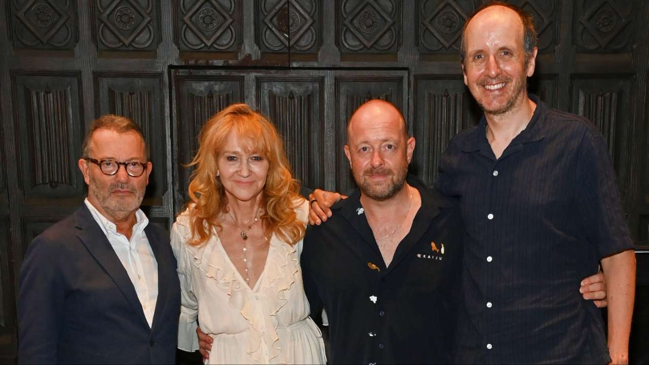 Colin Callender, Sonia Friedman, Jack Thorne and John Tiffany pose together backstage, arms around each other's shoulders, in front of a dark carved wooden panelled wall.