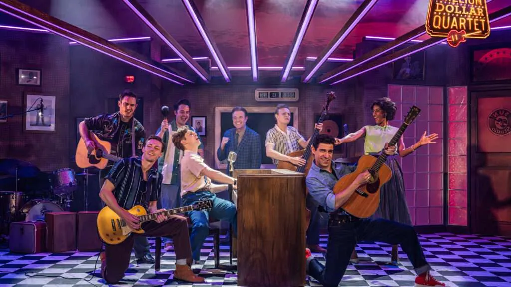 A lively vintage band rehearsal on a neon-lit stage with guitars, drums, and a microphone stand in a retro club setting.