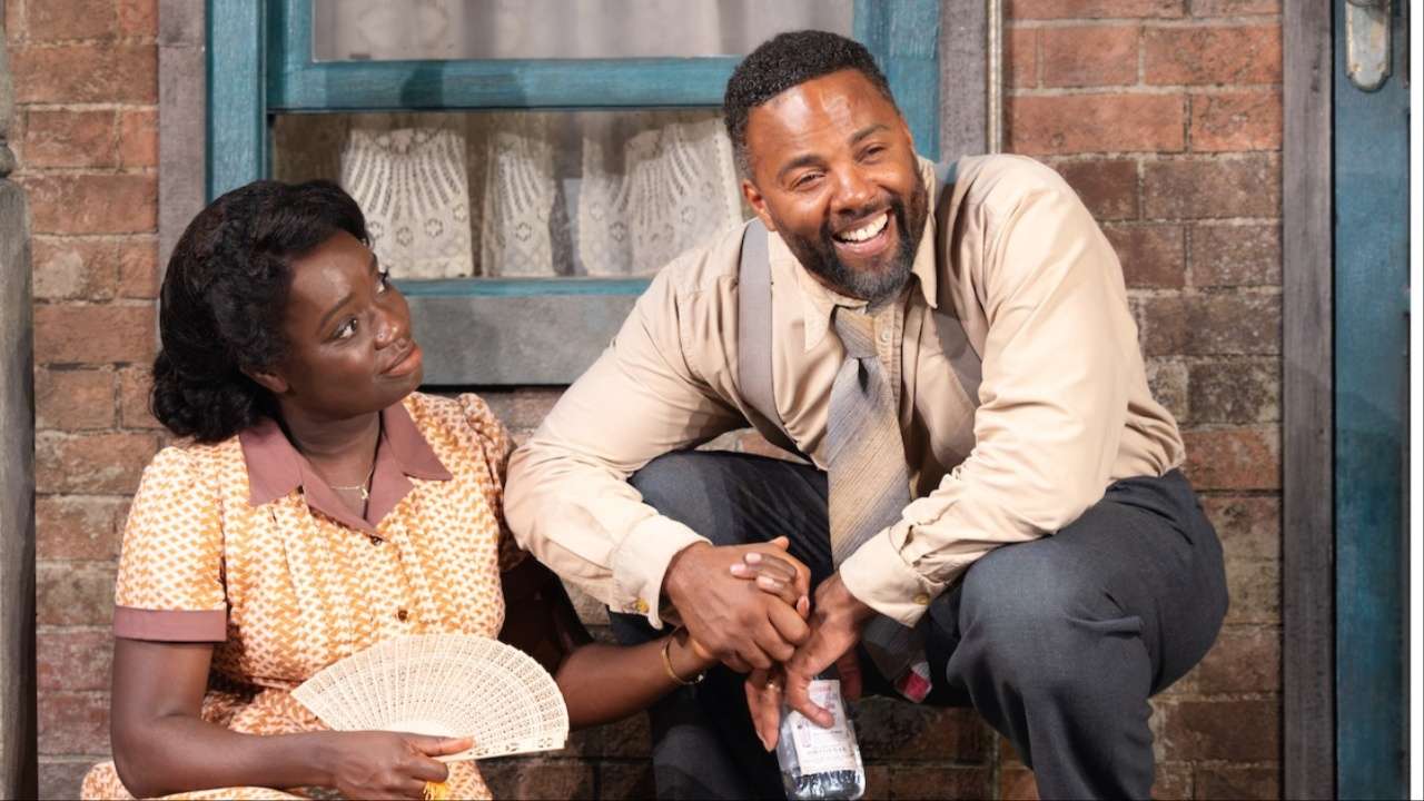 Woman in yellow dress smiling up at a man while they're sat on a house porch