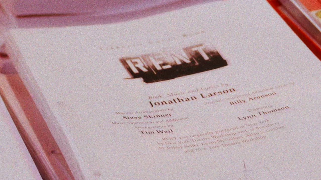 Close-up of a theater program page showing the name Jonathan Larson and a cast list nearby.